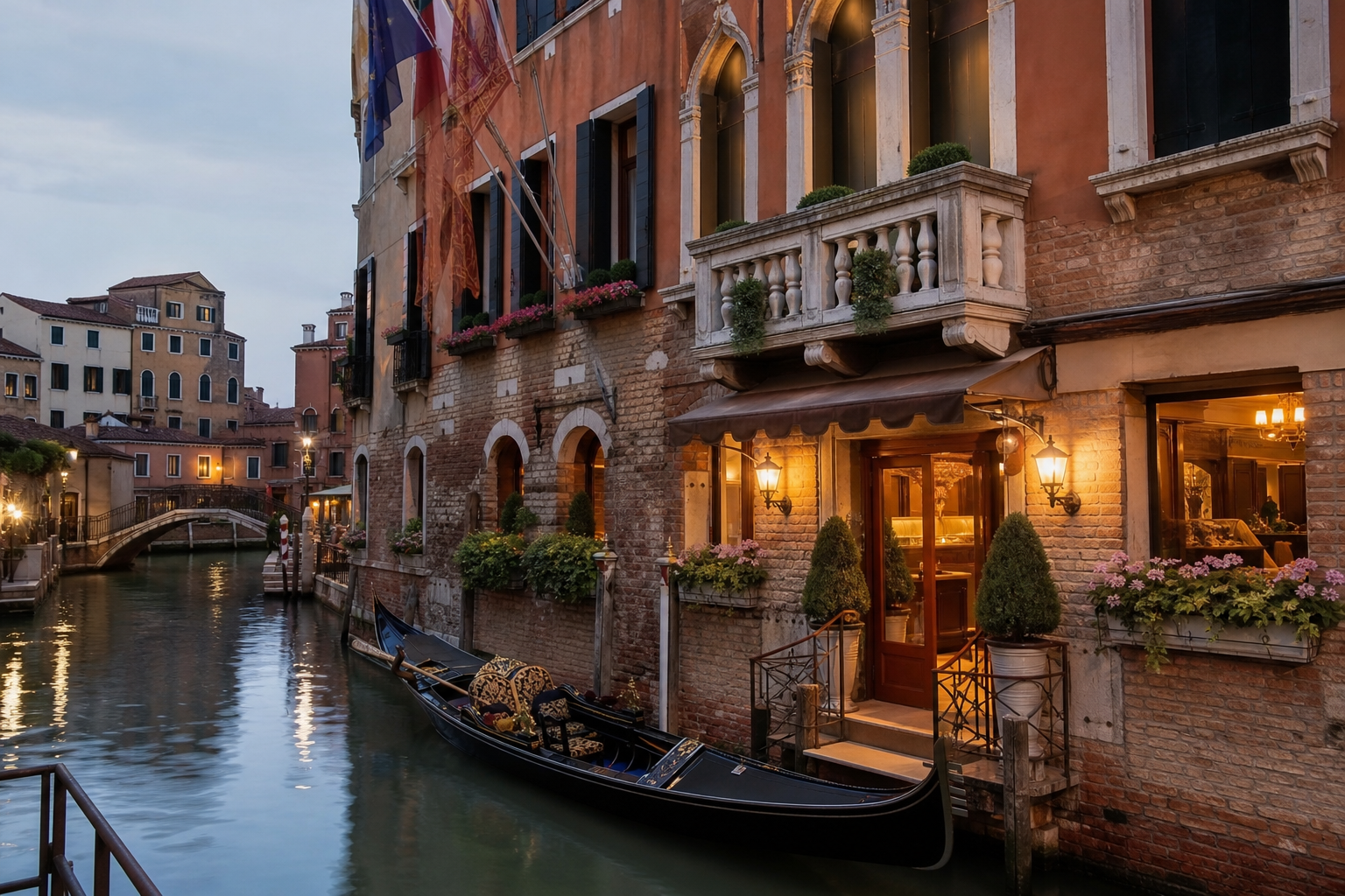 Quiet Venice canal at dusk with a small hotel facade, warm lit windows and a gondola moored nearby.